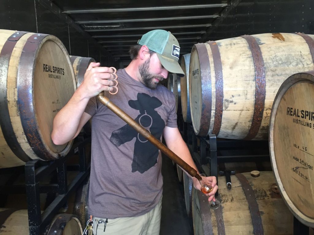 Davin pours Real Spirits whiskey from barrel
